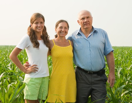 Happy family of three over a field of corn