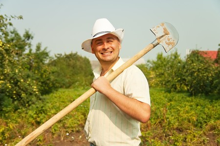 gardener posing  for the camera with his  shovel against summer time in gardenの写真素材