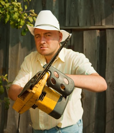 gardener posing  for the camera with his chainsaw against summer time in gardenの写真素材