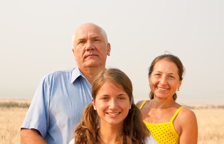Happy family of three over a field of wheat
