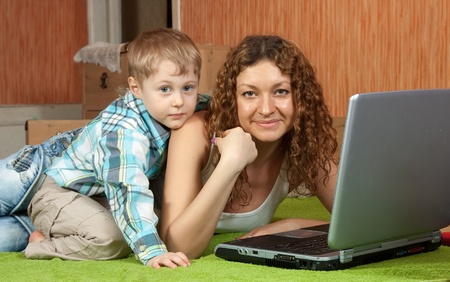 Happy mother and her son with laptop  in interiorの写真素材