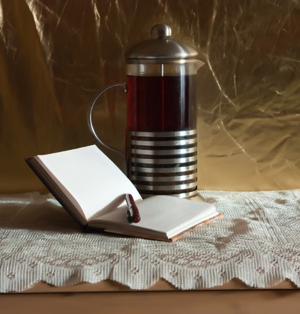 Teapot with notebook and pen on gold backdrop の写真素材