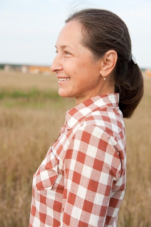 Portrait of happy senior woman against summer landscapeの写真素材