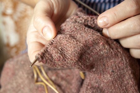 hands of  senior woman knitting in her room