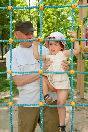 two-year child on  playground area and father nearの写真素材
