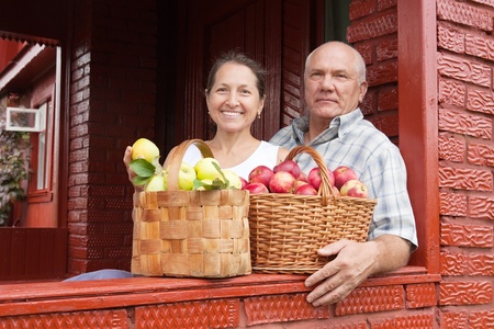 Happy elderly couple with   baskets   of applesの写真素材