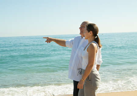 elderly couple walking by the hand along the seaの写真素材