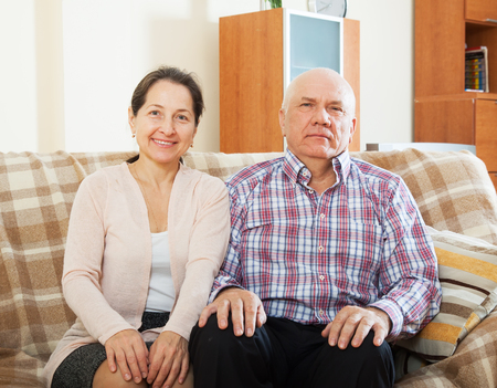 Happy mature woman with smiling husband in home interiorの写真素材