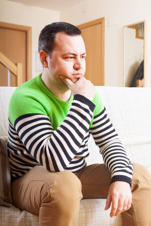 sad man sitting on the couch の写真素材