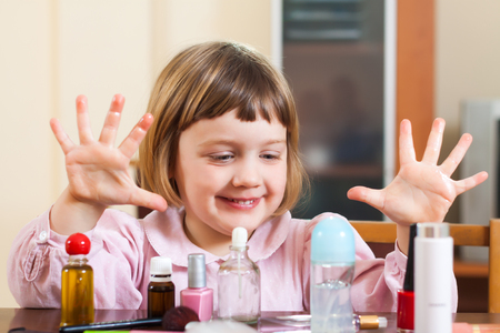 little girl at  table with cosmetic productsの写真素材
