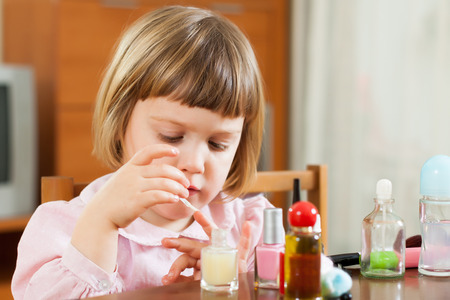 Beautiful three year old girl making manicureの写真素材