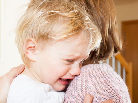 Mom soothing baby daughter in her armsの写真素材