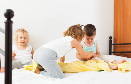 Two sisters and  brother having fun in white bed.の写真素材