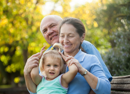Portrait of grandma and  grandpa with little grandaughter  outdoor