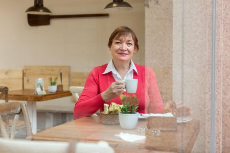 Mature woman drinking coffee in   cafe.の写真素材