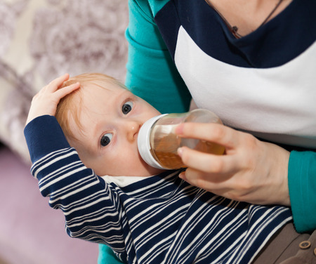 Mother feeding cute little son on her lap.の写真素材