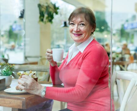 Portrait of senior  woman    sitting at   table in   cafe.の写真素材