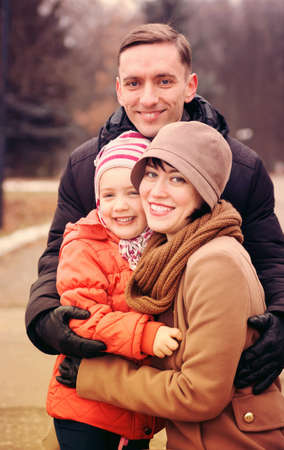 Happy young parents with   daughter  walking in   park in autumn.