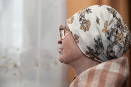 Lonely grandma in   scarf and glasses looking aside.の写真素材