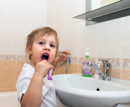 Portrait of child cleaning   teeth by   sink in bathroom.の写真素材