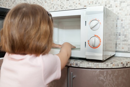 Little girl playing with dangerous kitchen applianceの写真素材