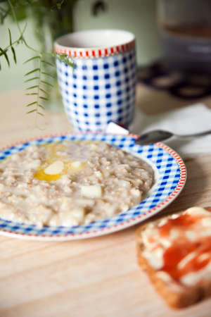 Still life of plate of porridge and   piece of bread with jam on  table.の写真素材