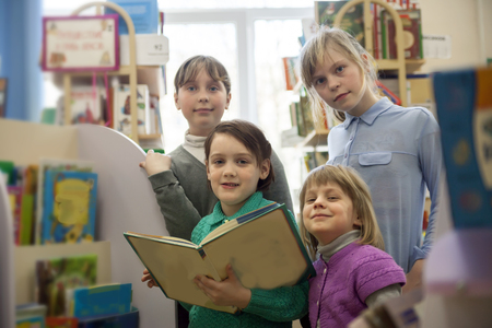  Four school girls reading   book in     library. の写真素材