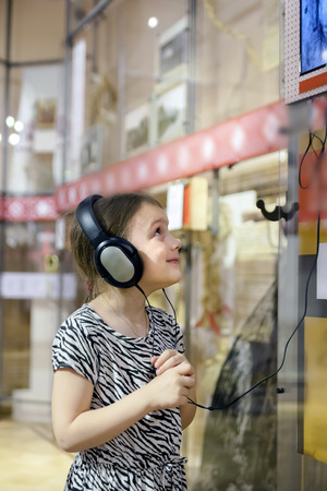   girl in   museum listening to interesting information about   exhibit through headphones.  の写真素材