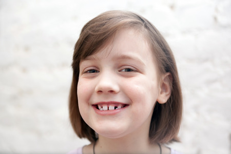 Portrait of   smiling seven year old girl on   white background.