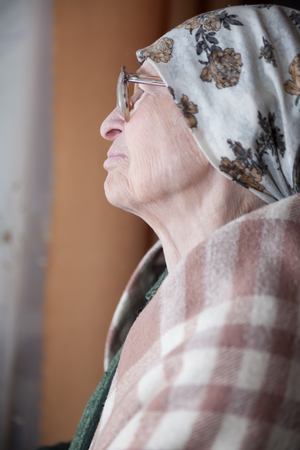  Lonely grandma in   scarf and glasses looking aside. の写真素材