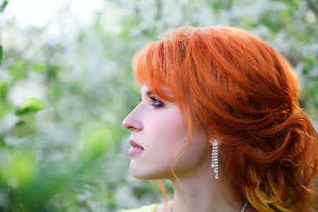 Portrait of   beautiful red-haired girl in blooming spring gardens.の写真素材