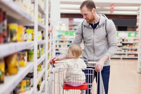 Father with   little daughter choosing   goods on   shelves of   supermarket.の写真素材