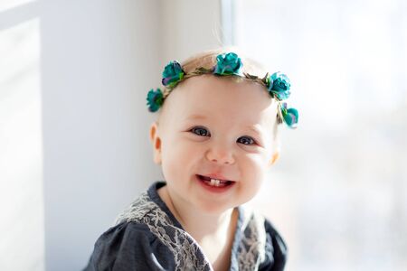 Portrait of   one-year-old girl in   wreath with flowers on   light backgroundの写真素材