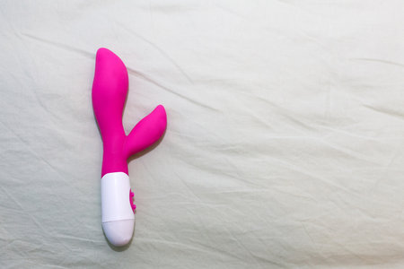 Silicone pink dildo vibrator on bedの写真素材