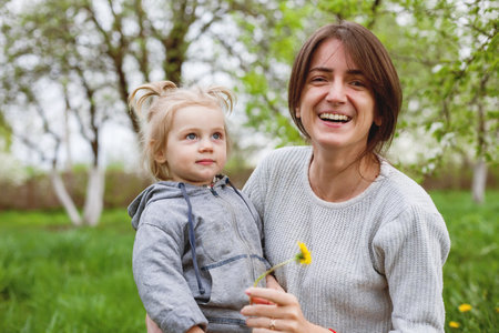 Portrait of young mother with baby in her arms in spring garden