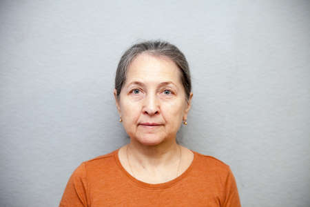 mature woman standing isolated above gray background of wall