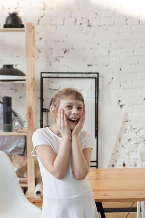 Pre-teen blonde girl holding her hands to face in surpriseの写真素材