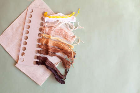 Beige canvas and set of colored floss threads on light background