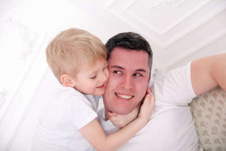 A little son of six hugging his dad at home.