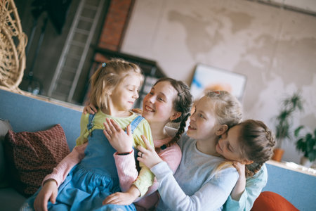Portrait of four girls schoolgirls girlfriends sitting on couchの写真素材