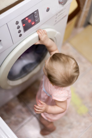 Dangerous situation with small child and washing machine in bathroomの写真素材