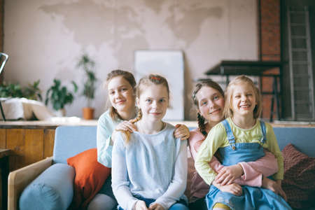 Portrait of four girls schoolgirls girlfriends sitting on couch