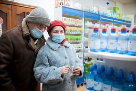 Portrait of couple of pensioners in pharmacy  in medical masks.の写真素材