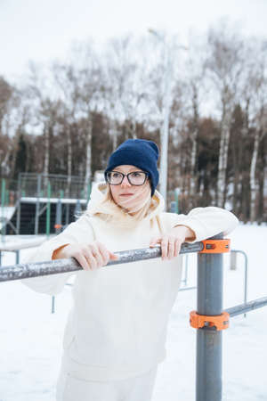 Girl in warm sports uniform training in winter park.
