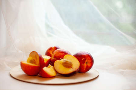 Still life of ripe nectarines,full and cut in half on light window background.の写真素材