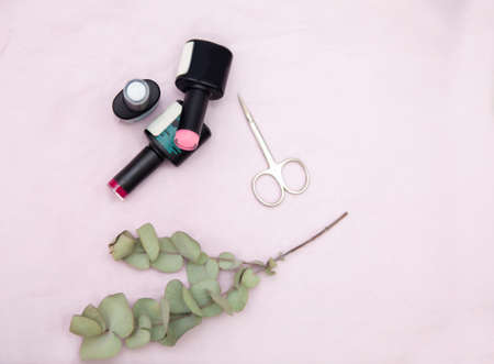 Nail salon table with manicure tools and nail polish bottles on pink background. Flat lay, top view....