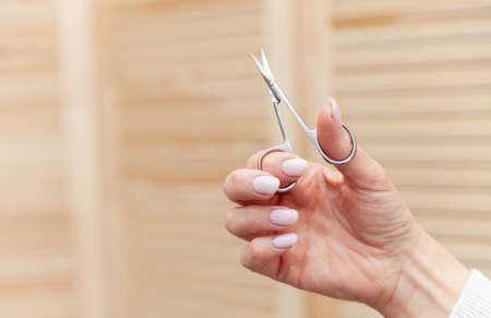 Manicure - Beauty treatment photo of nice manicured woman fingernails. Hands holding scissors