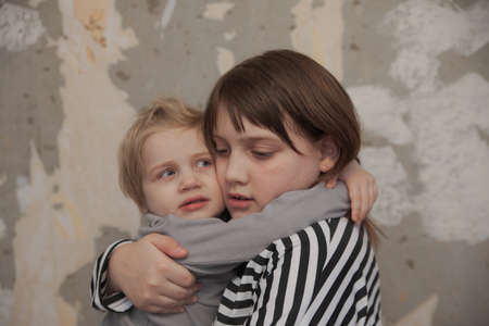 Frightened children standing against wall huddled togetherの写真素材