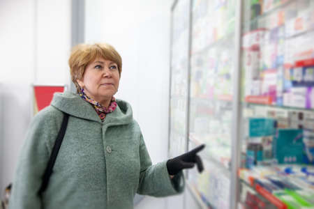 Portrait of mature woman in coat prescription buying drugs.の写真素材