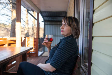 Portrait of beautiful mature woman on porch of her houseの写真素材